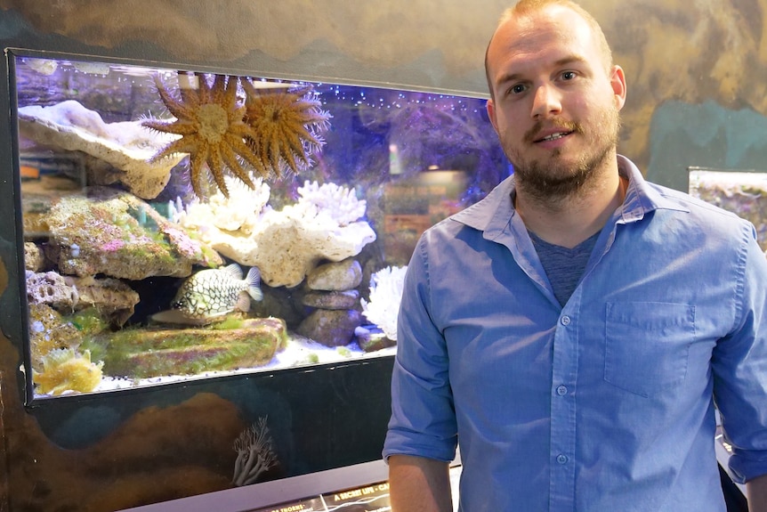 Dr. Benjamin Moss of Southern Cross University's National Marine Science Center stands in front of an aquarium.