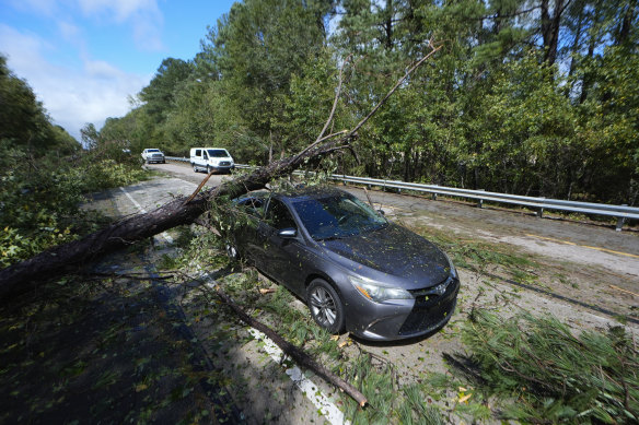 A tree rests on top of an abandoned car on Interstate 20 after Hurricane Helen.